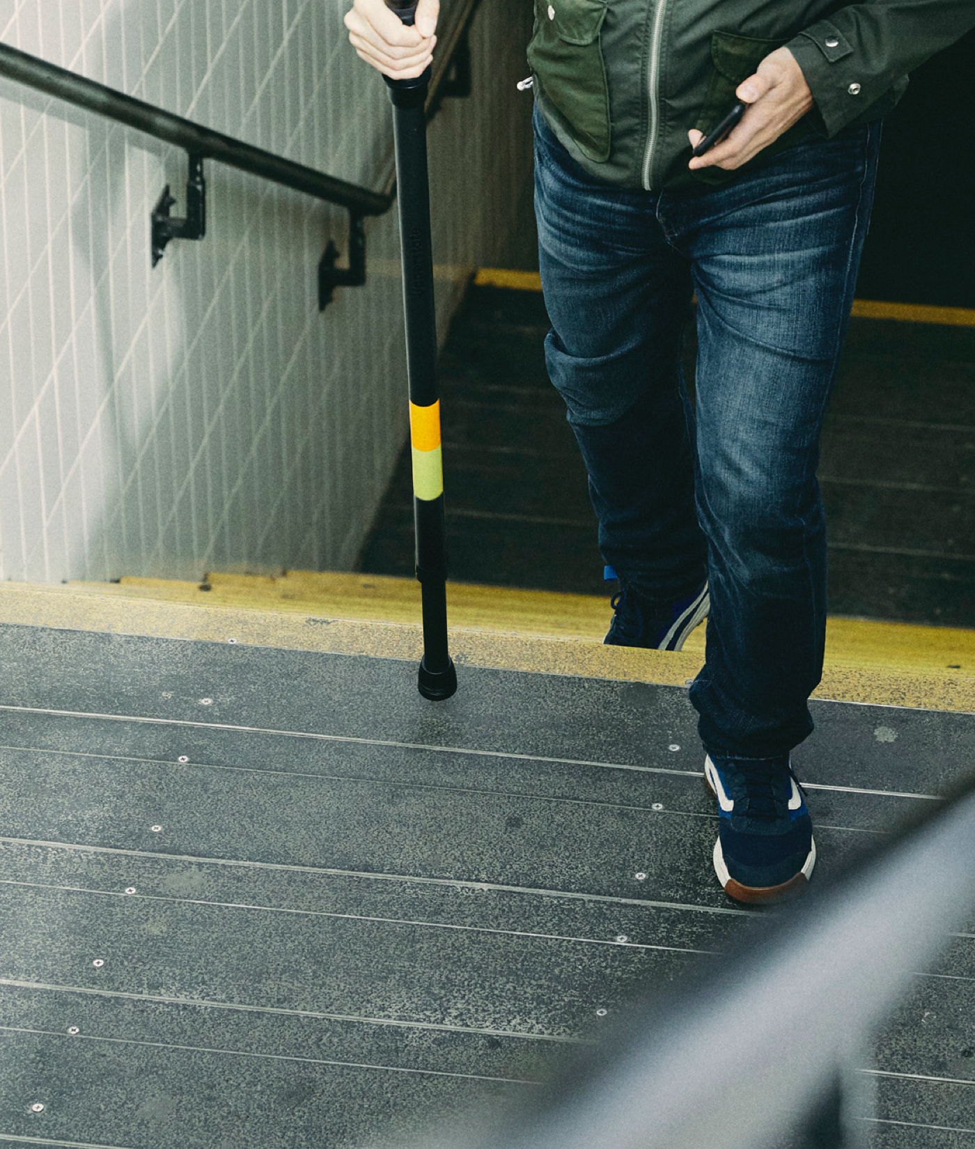 Photo of person walking up stairs using an Upperstate pole to help with balance.